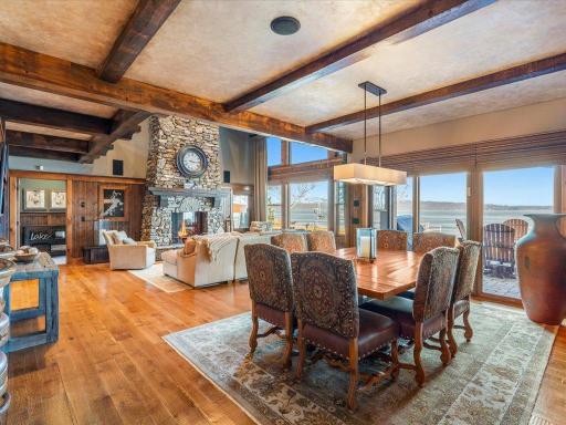 Elegant dining area with lake views, exposed beams, and open flow into the great room and stone fireplace.
