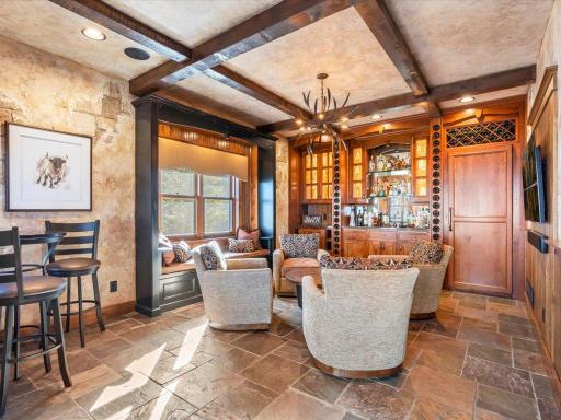 Elegant lounge with custom cabinetry, wood beam ceilings, and sunlit reading nook.
