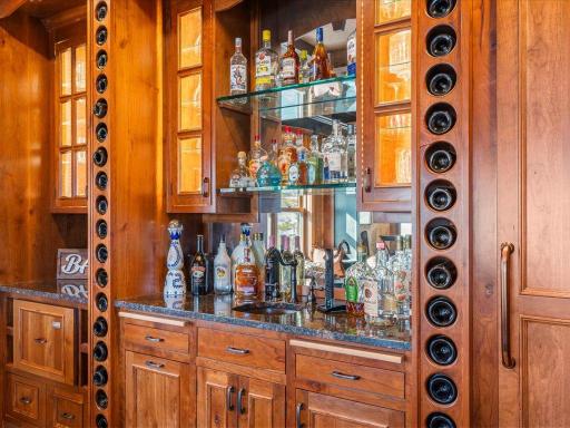 Built-in bar with wine storage, mirrored backsplash, and custom glass shelving.