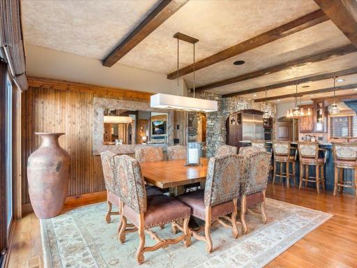Formal dining area with wood beam accents, elegant lighting, and open flow into the great room.