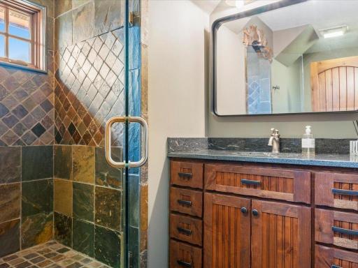 Rustic-inspired bathroom with slate tile shower, wood vanity, and granite countertop.