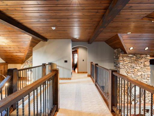 Upper-level catwalk with stone and wood accents overlooking main living areas.