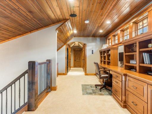 Open loft with tongue-and-groove ceiling, built-in workspace, and rustic trim accents.