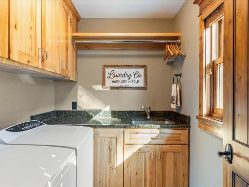 Charming laundry room with built-in cabinetry, granite counters, and natural light.