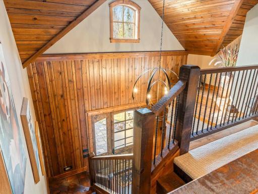 Custom staircase with wood paneling and wrought iron balusters, filled with natural light.