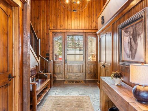 Grand entryway with rich wood paneling, custom double doors, and charming lodge-style details.