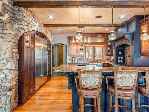Expansive kitchen with arched stone entry, dual islands, and built-in luxury appliances.
