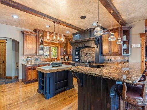 Stylish kitchen with granite countertops, custom vent hood, and pendant lighting over a central prep island.