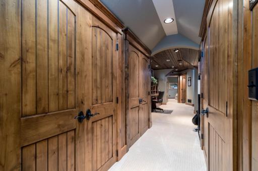 Upper-level hallway with custom wood doors and vaulted ceiling detail.