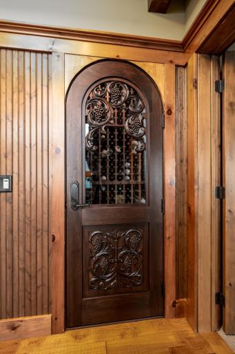 Custom arched wine cellar entry with hand-carved wood door and wrought iron detail.