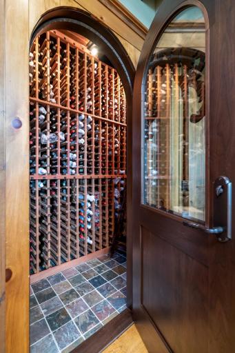 Walk-in wine cellar with floor-to-ceiling bottle storage and glass-paneled entry.