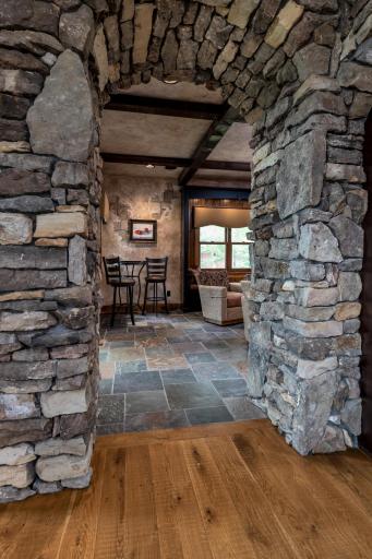Lower-level entertaining area framed by stunning stone archways and slate flooring.
