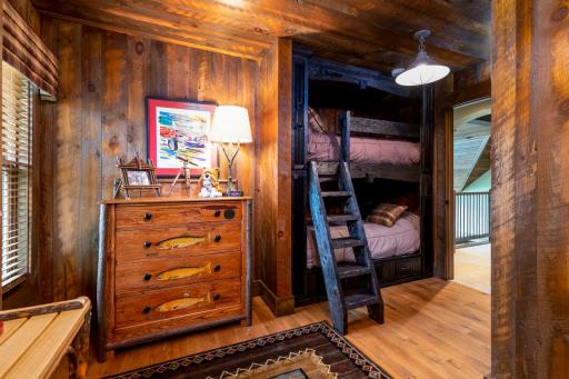 Rustic bunk room with built-in twin beds, custom wood paneling, and cozy cabin charm.