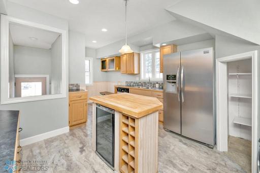 Kitchen island offers a wine fridge & storage with butcher block counter
