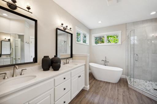 The spacious walk-in shower and deep soaking tub invite moments of quiet indulgence, while a dual bowl vanity offers ample space for daily routines.