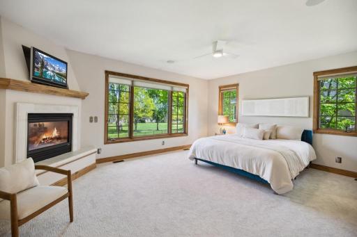 Situated on the main floor, the primary bedroom offers a serene retreat bathed in natural light, with expansive windows that frame peaceful views of the golf course and pond.