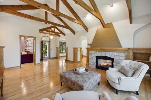 The living room offers a sophisticated yet welcoming atmosphere, anchored by a double-sided gas fireplace and accented with striking wood beams and hardwood floors.