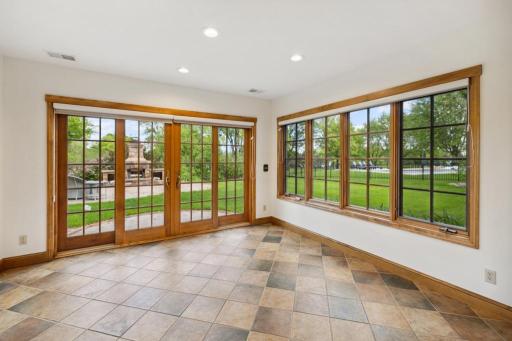 he lower-level sunroom blurs the line between indoors and out, with walls of glass that open to a custom paver patio and wood-burning fireplace.