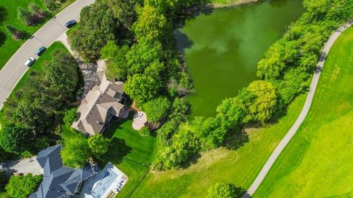 This aerial view reveals the full scope of the setting: a private, well-appointed backyard framed by mature trees, with tranquil pond views and sweeping vistas of the Prestwick golf course unfolding just beyond.