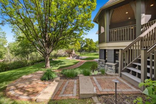 From the screened porch, a set of steps leads to a thoughtfully designed paver path, guiding you through the backyard toward the custom patio and wood-burning fireplace.