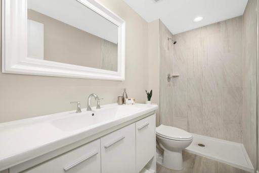 Freshly remodeled bath with new shower, tile, flooring, vanity, mirror, and lighting.