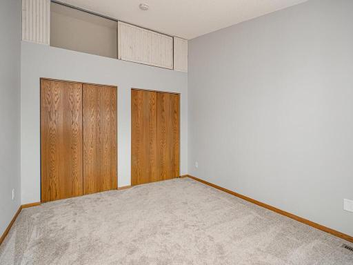 The second bedroom also with vaulted ceilings and generous storage, with two full closets, and an additional storage space above.