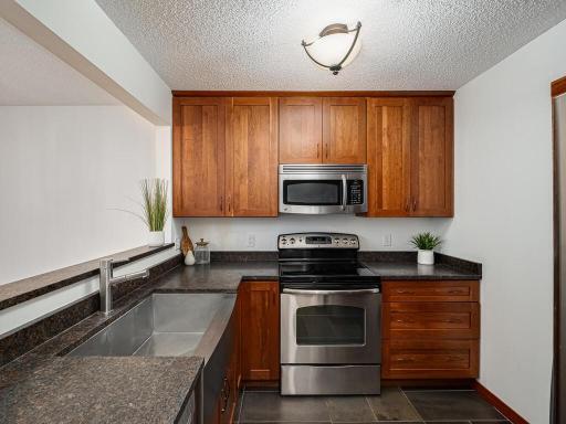 Beautifully updated kitchen with shaker-style wood cabinets, stone countertop and gorgeous tile floors to match.