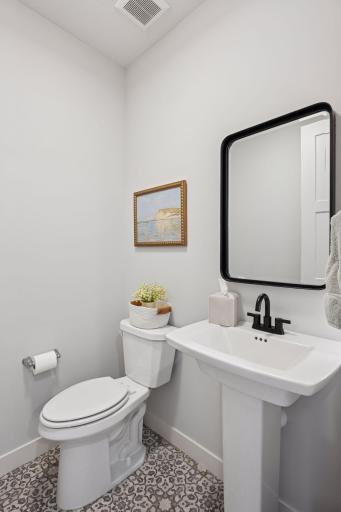 The main floor 1/2 bath features a pedestal sink with mirror and over head lighting.
