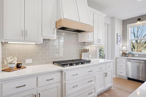 The kitchen offers ample cabinet and counter space, complemented by a stylish tile backsplash that adds both function and flair.