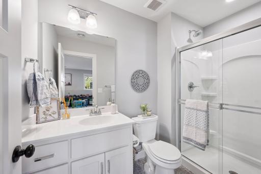 The lower level 3/4 bath features vanity sink with mirror, wall lights, a convenient walk in shower and luxury vinyl flooring.