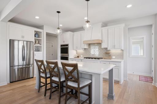 The kitchen boasts a walk in pantry (around the corner), and granite countertops, a casual eating space on the large island, double wall oven and stainless steel appliances. The window to the right looks into the sport court.