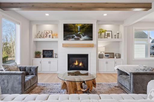 The living room offers recessed lighting, a cozy gas fireplace with built in storage on either side, a large picture window, and wood flooring throughout.