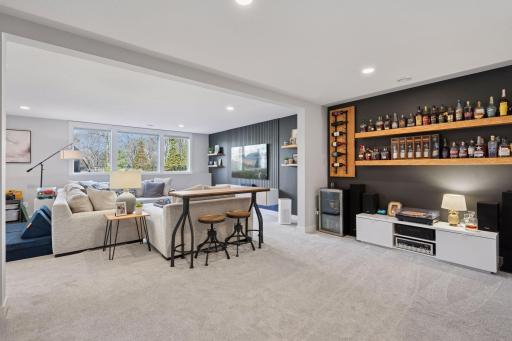 The lower level family room features carpeted flooring, lookout windows, recessed lighting, a feature wall with built in shelves and plenty of space for entertaining.