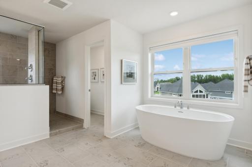(Photo of model home, finishes will vary). A freestanding tub and rain glass window is perfect for sun-dappled soaks and rejuvenation
