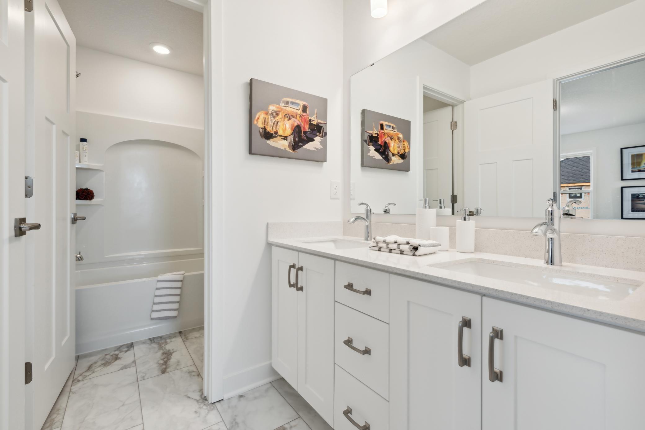 (Photo of model home, finishes will vary)This full-sized bathroom features a vanity with convenient dual sinks that close off from the shower and tub combo for extra privacy. It is directly accessible from an adjacent bedroom.