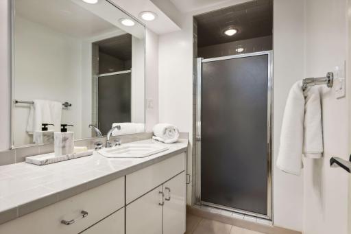 The three-quarter bath on the lower level has ceramic tile accents, a large vanity, and a step-in shower.