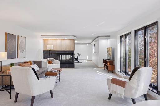 The three-sided decorative fireplace divides the space, creating a separate area for an exercise room or a playroom.