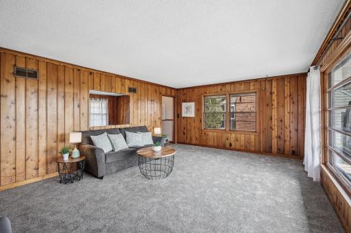 This home features a spacious living room with a large picture window, charming knotty pine walls, brand new carpeting, and an abundance of natural light.