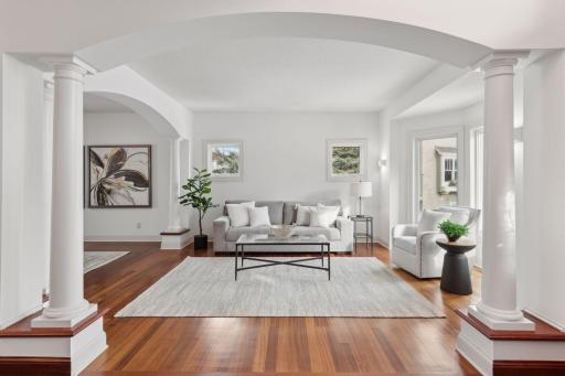 An open floor plan bathed in natural light, accented by rich wood finishes and elegant columns, creates a warm and inviting atmosphere perfect for both living and entertaining.