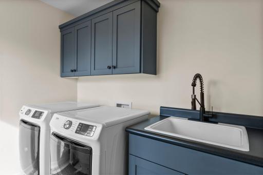 Updated laundry room with painted cabinetry, extra deep wash sink and new lighting.