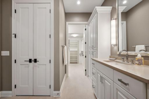 This primary bathroom boasts ample storage, expansive counter space, and direct access to the walk-in closet