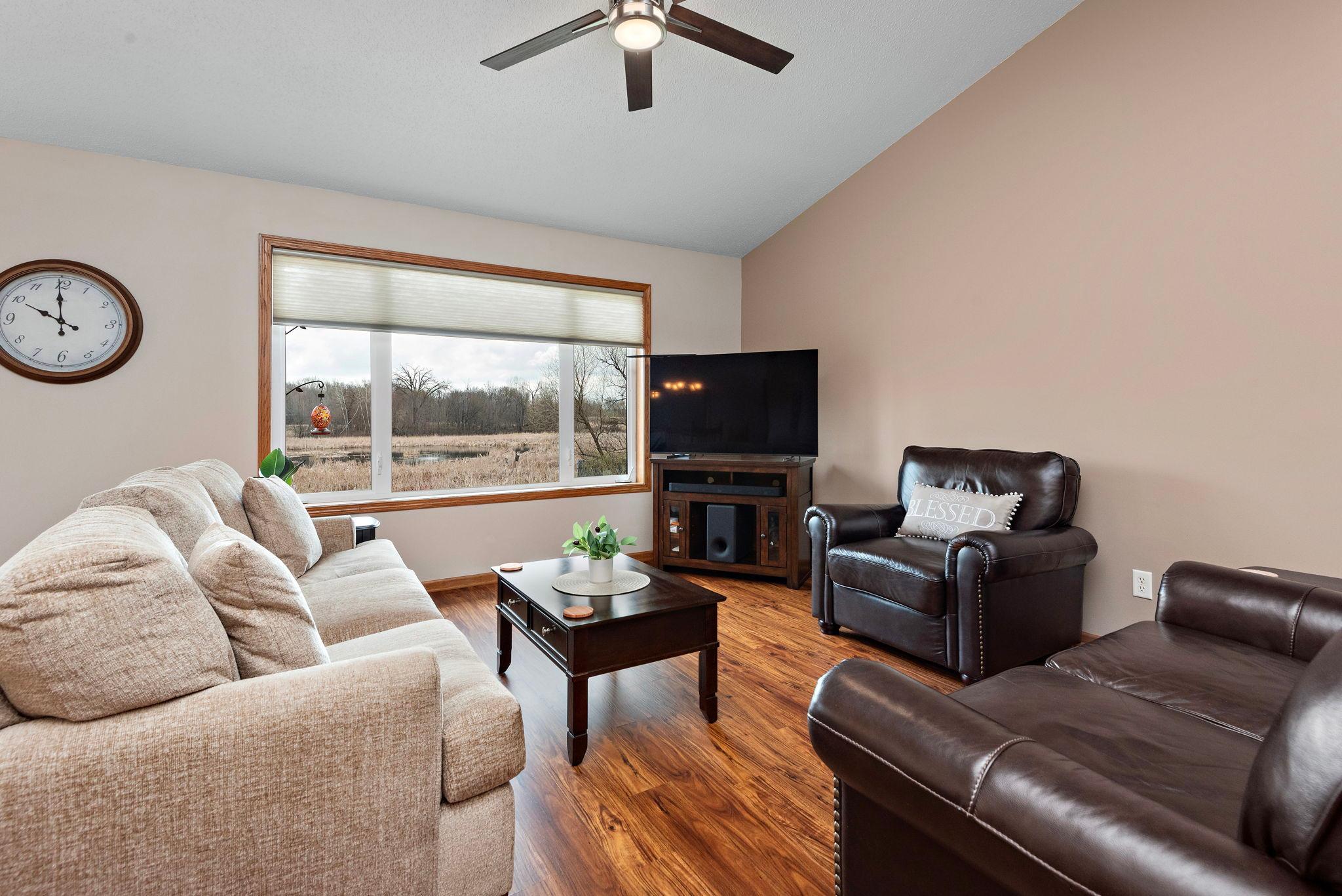 Main Floor Living room has vaulted ceilings, newer ceiling fan, newer flooring, views to back yard and sliding glass door to deck with steps to back private yard!