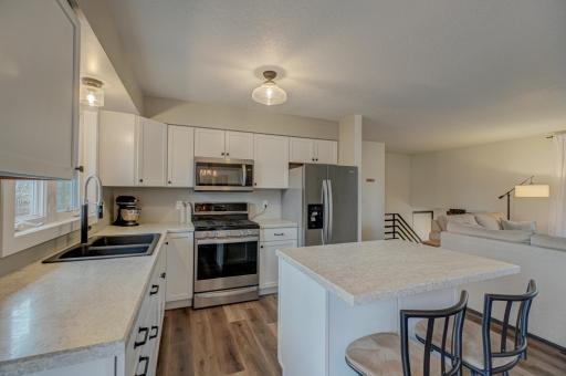 The bright, contemporary kitchen boasts a spacious center island, stainless steel appliances, and ample counter and cabinet space, perfect for both cooking and entertaining.
