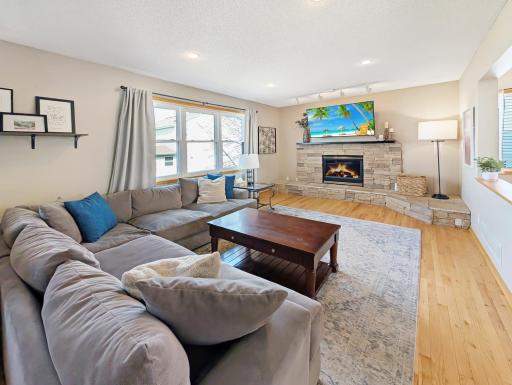 Living room also features a beautiful stone fireplace with spotlights highlighting it.
