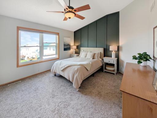 Spacious master bedroom with large windows and ceiling fan with light.