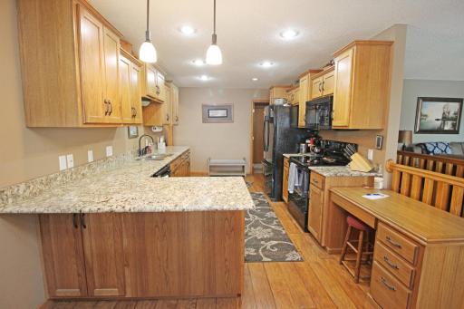 Beautifully updated kitchen with granite tops, custom cabinets, wood flooring, and recessed lighting.