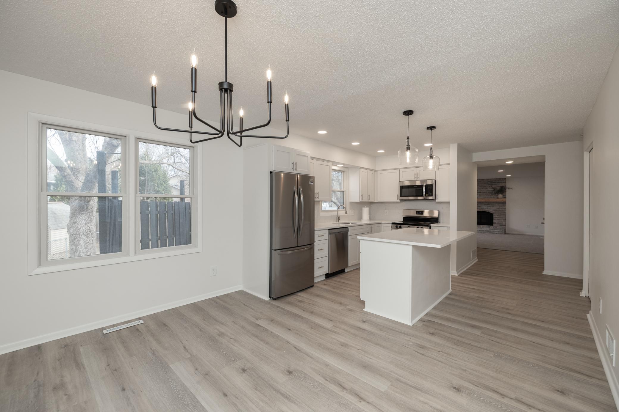 Dining room and kitchen with new LVP flooring, lighting and paint