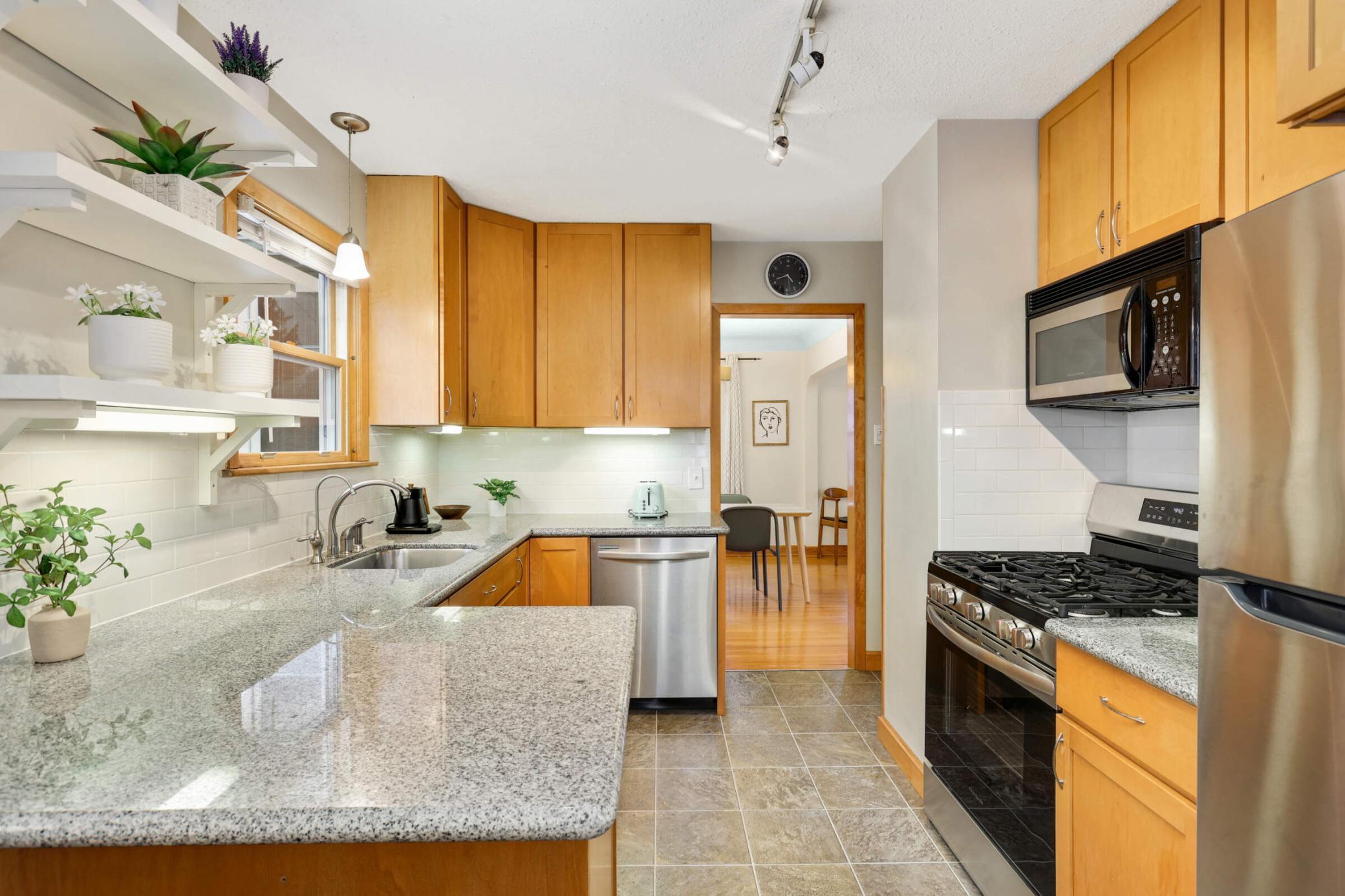 Beautifully updated kitchen featuring granite countertops, stainless steel appliances, and open shelving designed for both function and style.