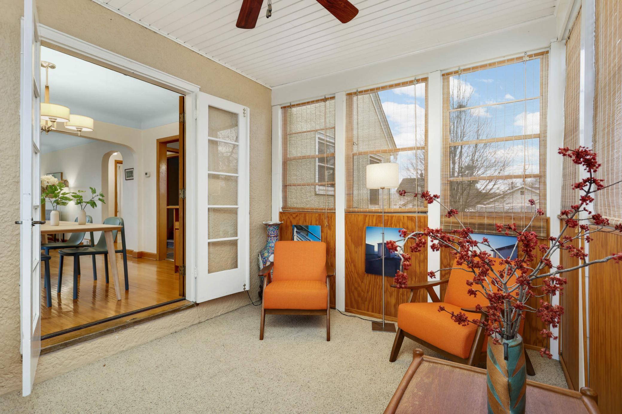 Cozy 3-season porch with french doors, ceiling fan, and carpeting, offering the perfect space to relax and unwind while enjoying tranquil views of the backyard.
