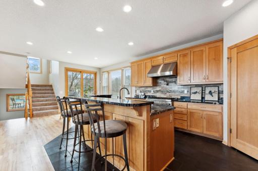 A large kitchen with granite countertops, maple cabinetry, slate floors and a walk in pantry.